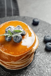 Tasty pancakes with berries and honey on slate plate