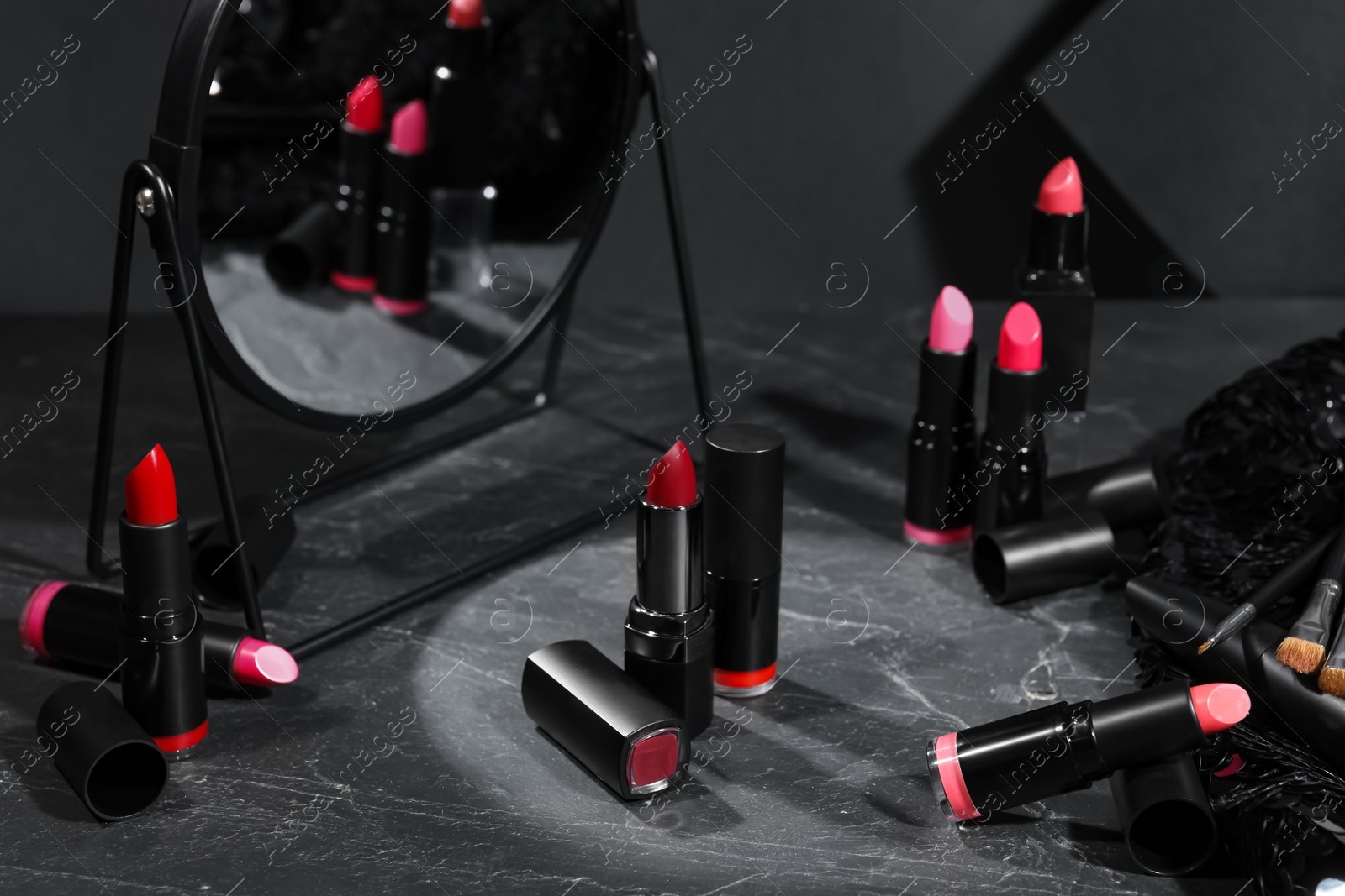 Photo of Different beautiful lipsticks and mirror on grey marble table