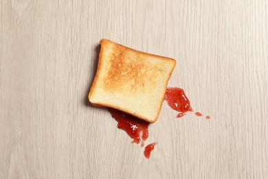 Photo of Overturned toast bread with jam on floor, top view