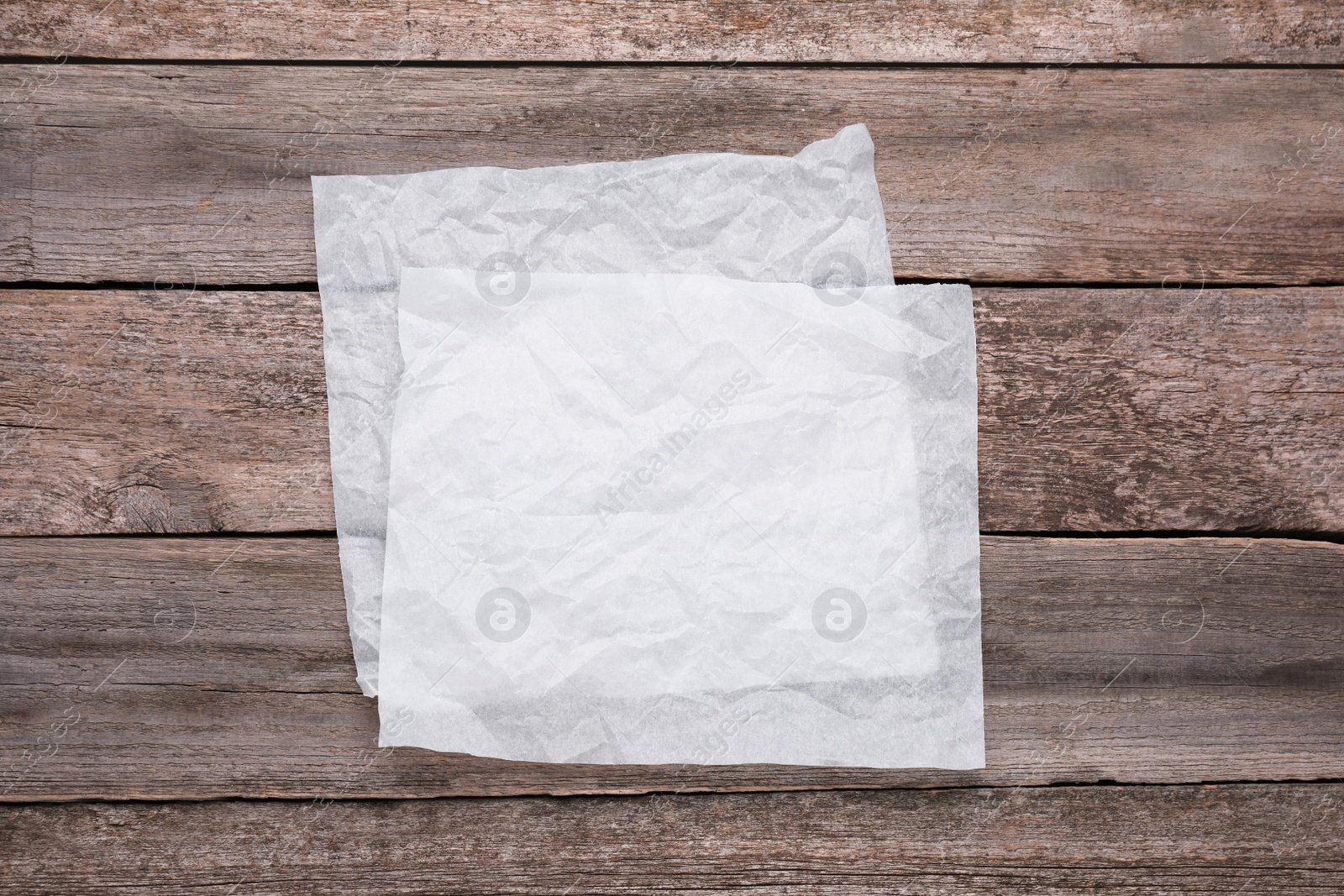 Photo of Sheets of baking paper on wooden table, top view