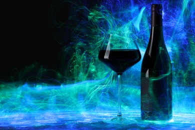 Photo of Red wine in glass and bottle in color lights on black background, space for text