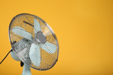 Photo of Modern electric fan on yellow background. Space for text