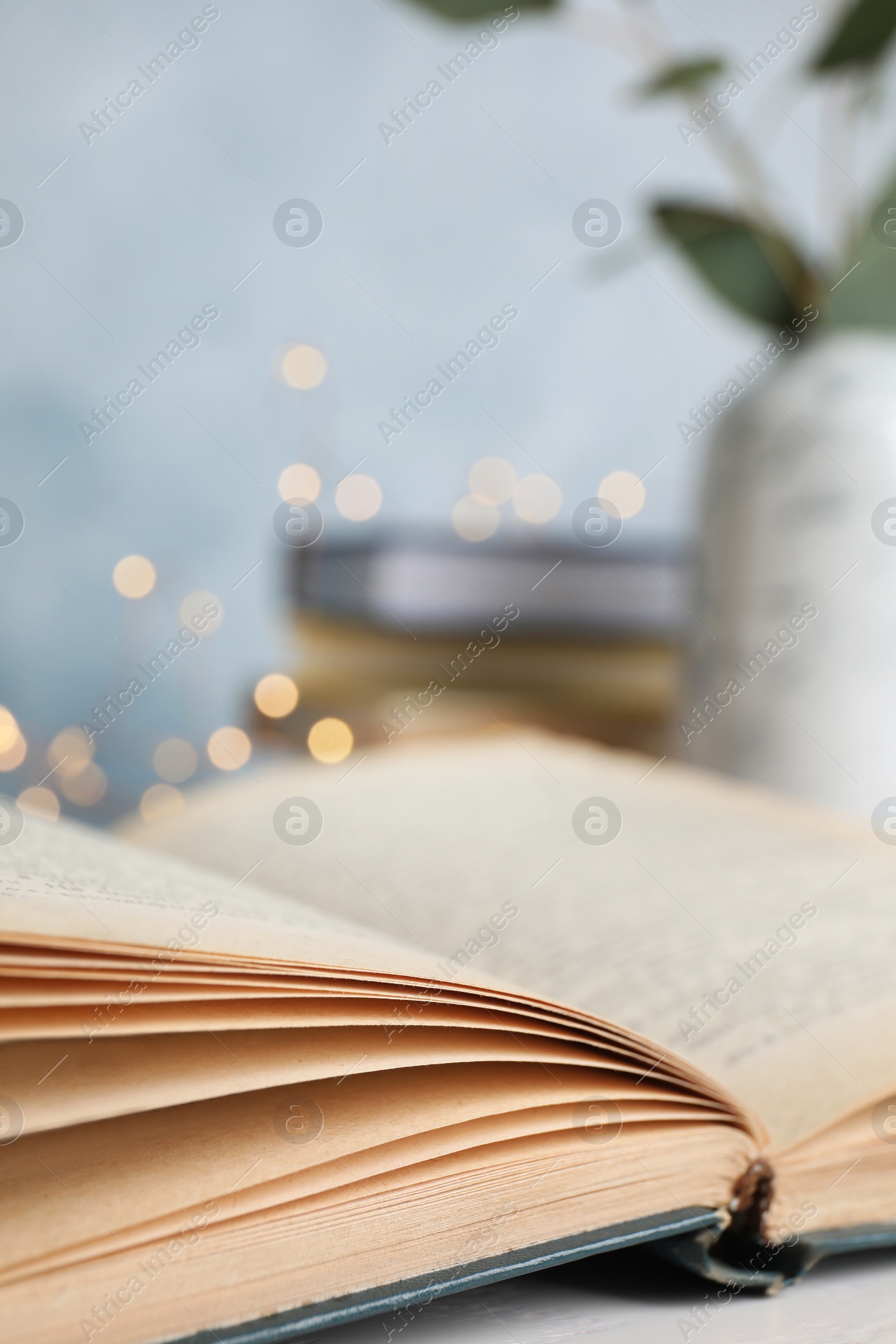 Photo of Open hardcover book on table against blurred background, closeup