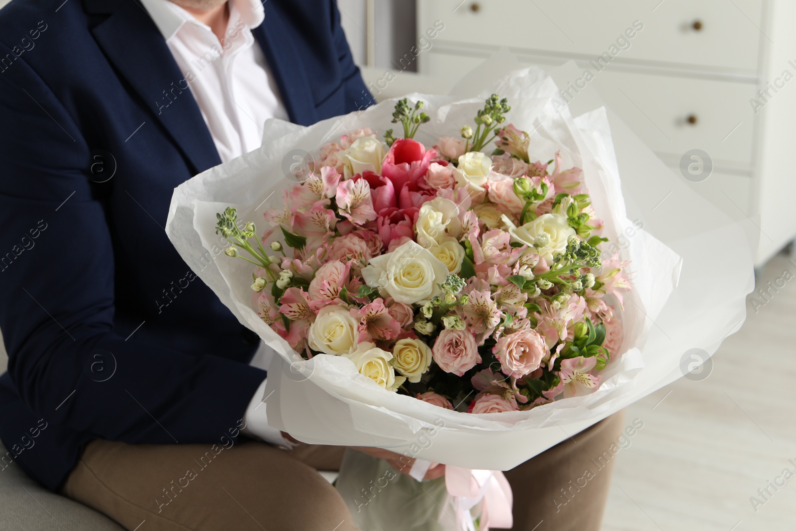 Photo of Man with beautiful bouquet of flowers indoors, closeup