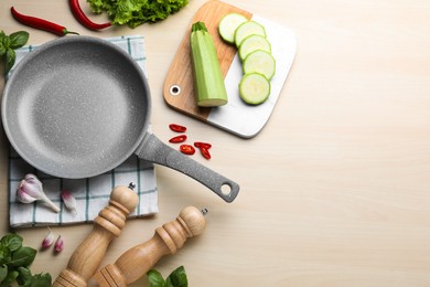Photo of Empty frying pan, fresh vegetables and basil on wooden table, flat lay. Space for text
