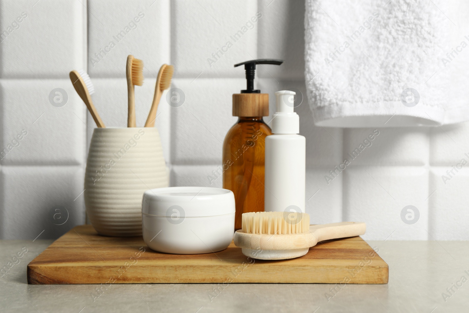 Photo of Different bath accessories and personal care products on gray table near white tiled wall