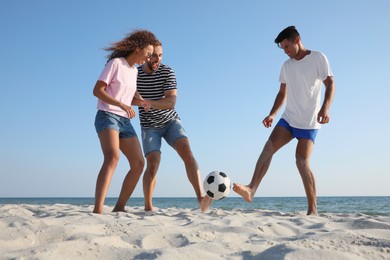 Group of friends playing football on beach