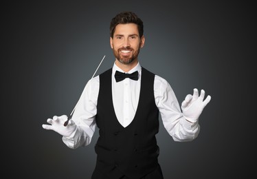 Happy professional conductor with baton on black background