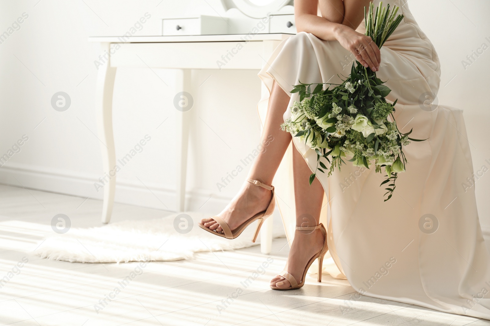 Photo of Young bride wearing wedding dress with beautiful bouquet in room, closeup. Space for text