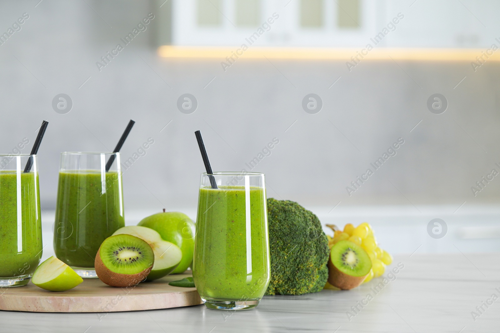 Photo of Delicious fresh smoothie and ingredients on white marble table in kitchen. Space for text