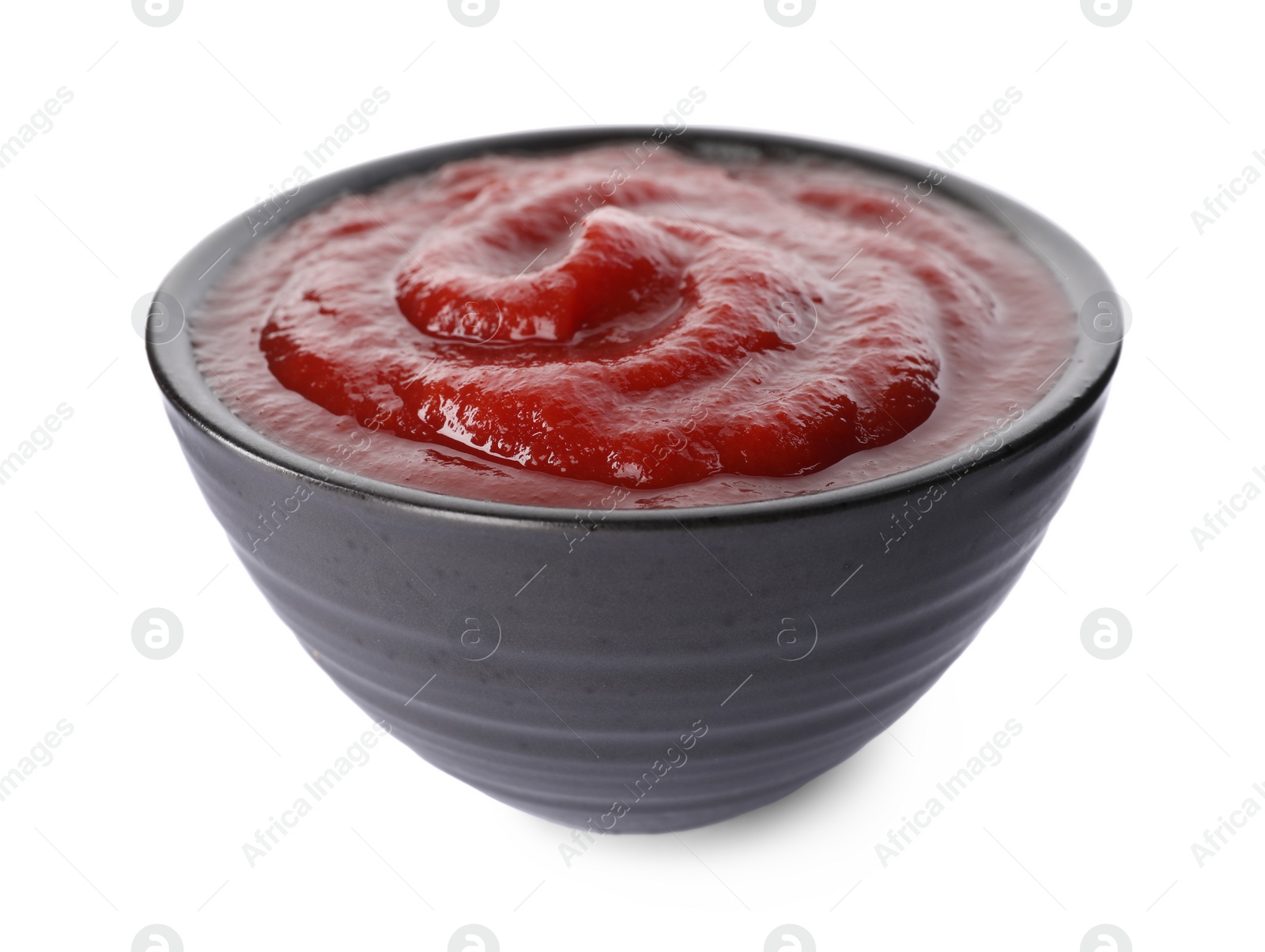 Photo of Tasty ketchup in bowl isolated on white, closeup