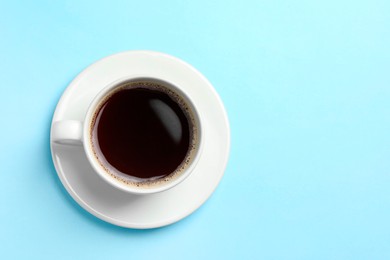 Cup of aromatic coffee on light blue background, top view. Space for text