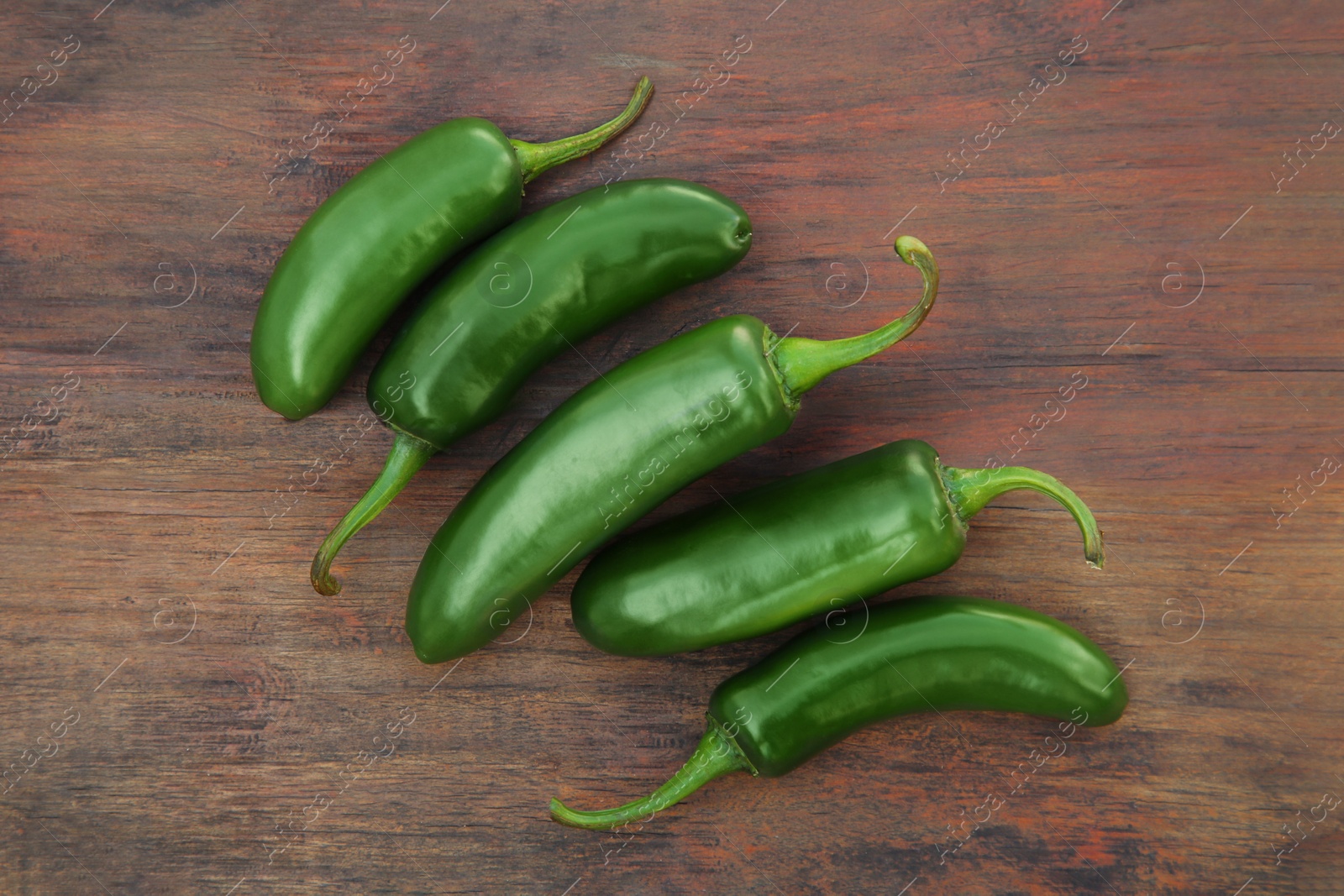 Photo of Fresh green jalapeno peppers on wooden table, flat lay