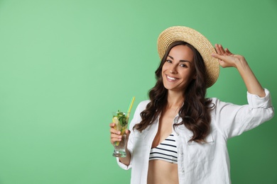 Young woman with refreshing drink on green background. Space for text