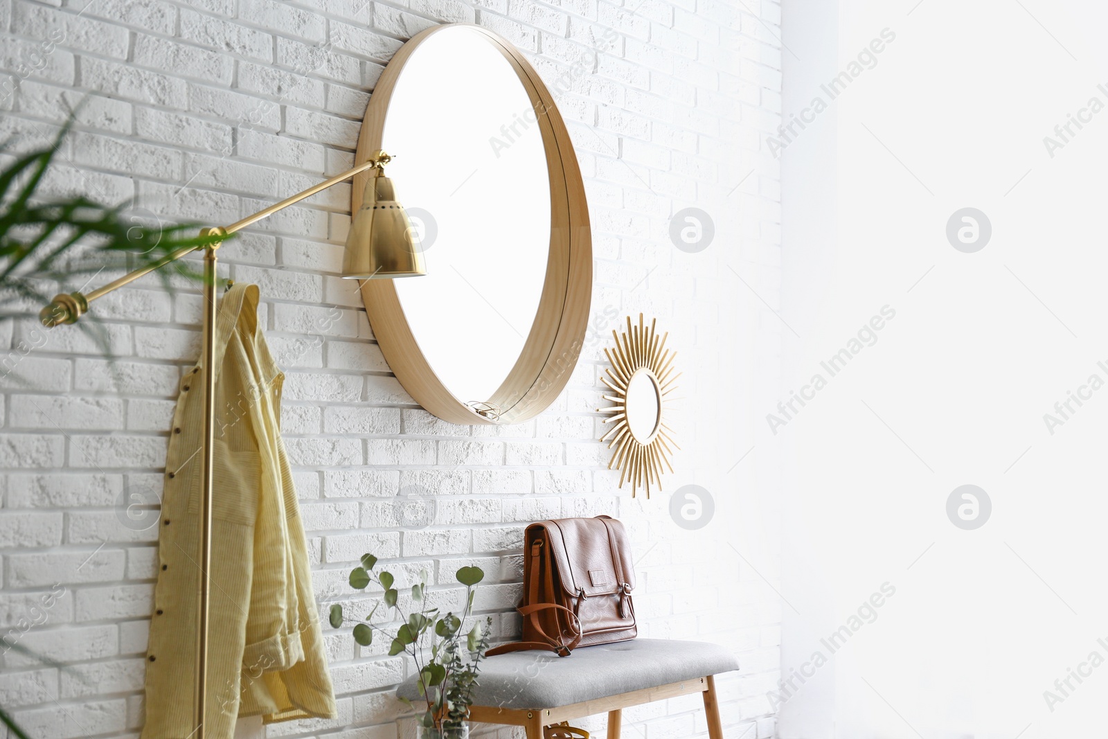 Photo of Room interior with round mirror hanging on brick wall. Space for text