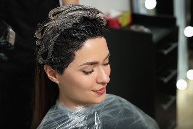 Photo of Professional hairdresser dyeing client's hair in beauty salon