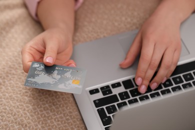 Photo of Woman with credit card using laptop for online shopping on bed, closeup
