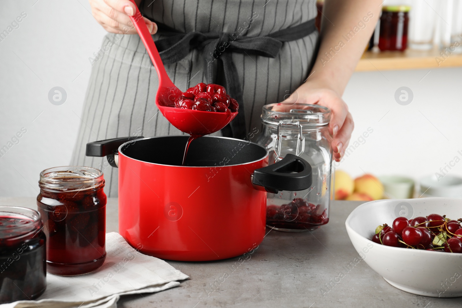 Photo of Woman making pickled cherries at table indoors, closeup