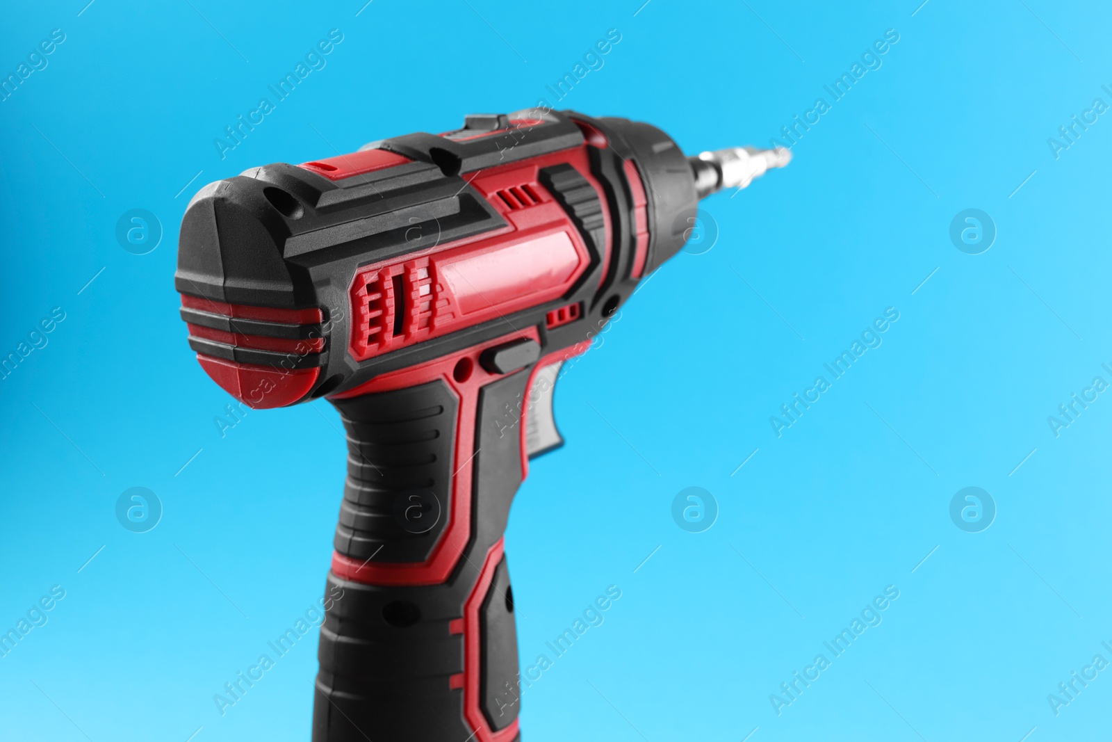 Photo of Modern electric screwdriver on light blue background, closeup. Space for text