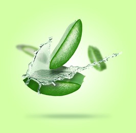 Image of Sliced aloe vera leaf and splash of juice on green background