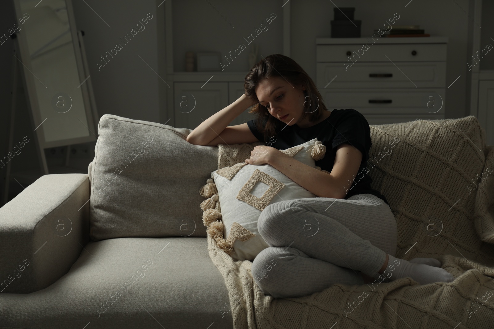 Photo of Sad young woman sitting on sofa at home