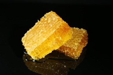 Photo of Natural honeycombs with tasty honey on black background, closeup