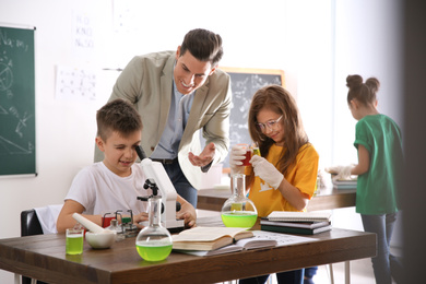 Teacher with pupils at chemistry lesson in classroom