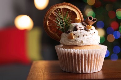 Photo of Beautifully decorated Christmas cupcake on wooden table indoors, closeup. Space for text