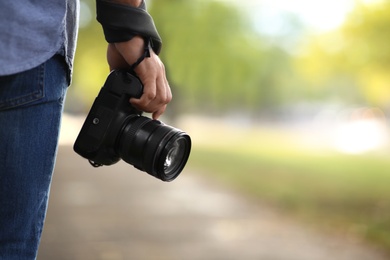 Photographer with professional camera in park, closeup