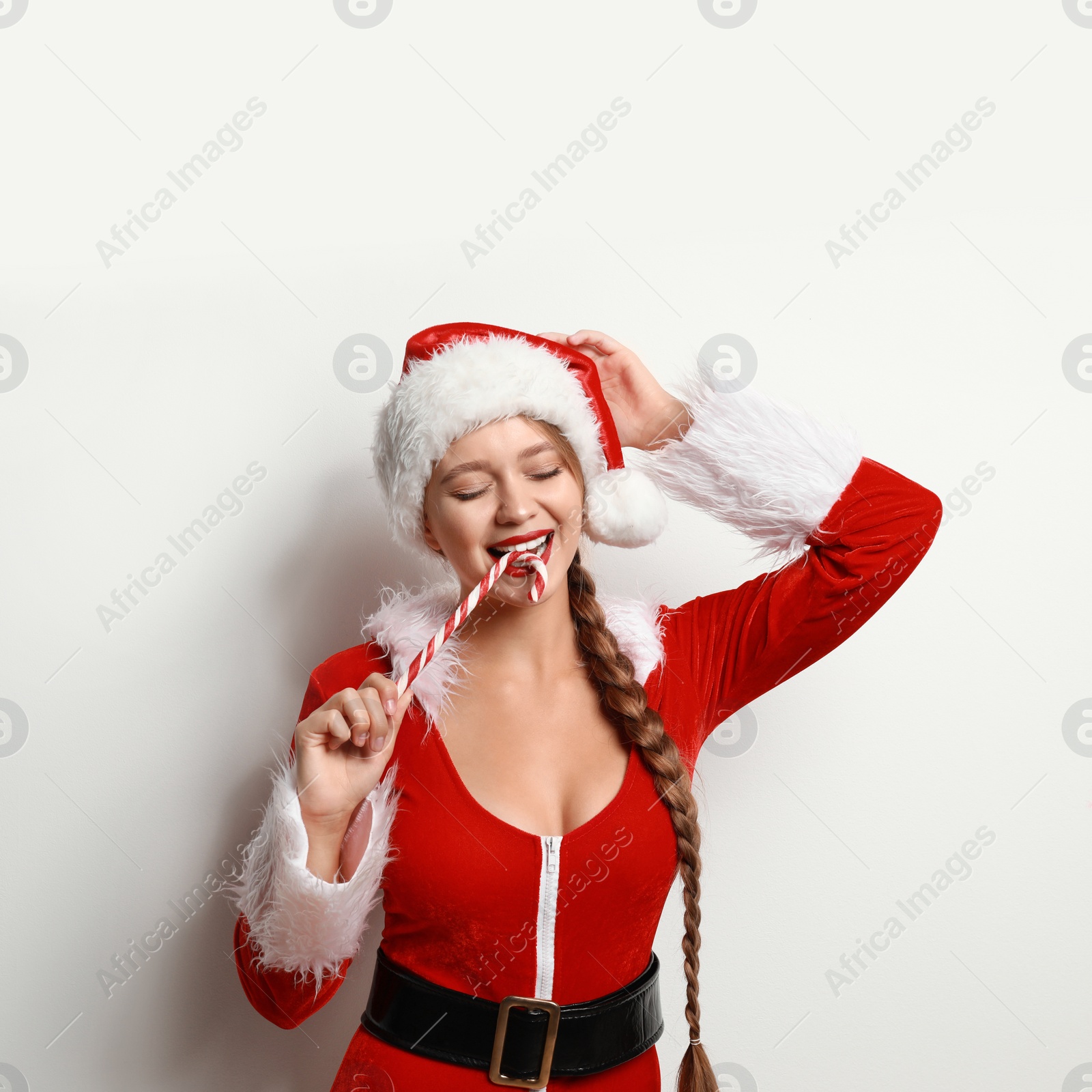 Photo of Beautiful Santa girl with candy cane on light background. Christmas eve