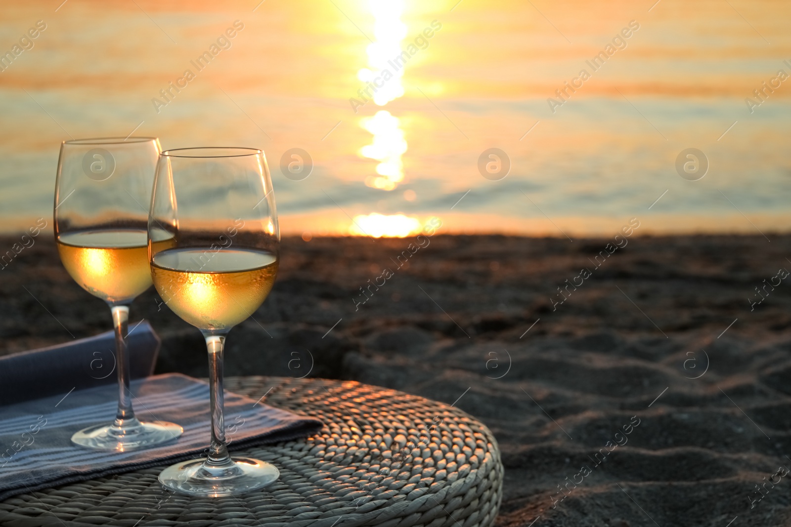 Photo of Glasses of delicious wine on riverside at sunset