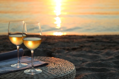 Photo of Glasses of delicious wine on riverside at sunset