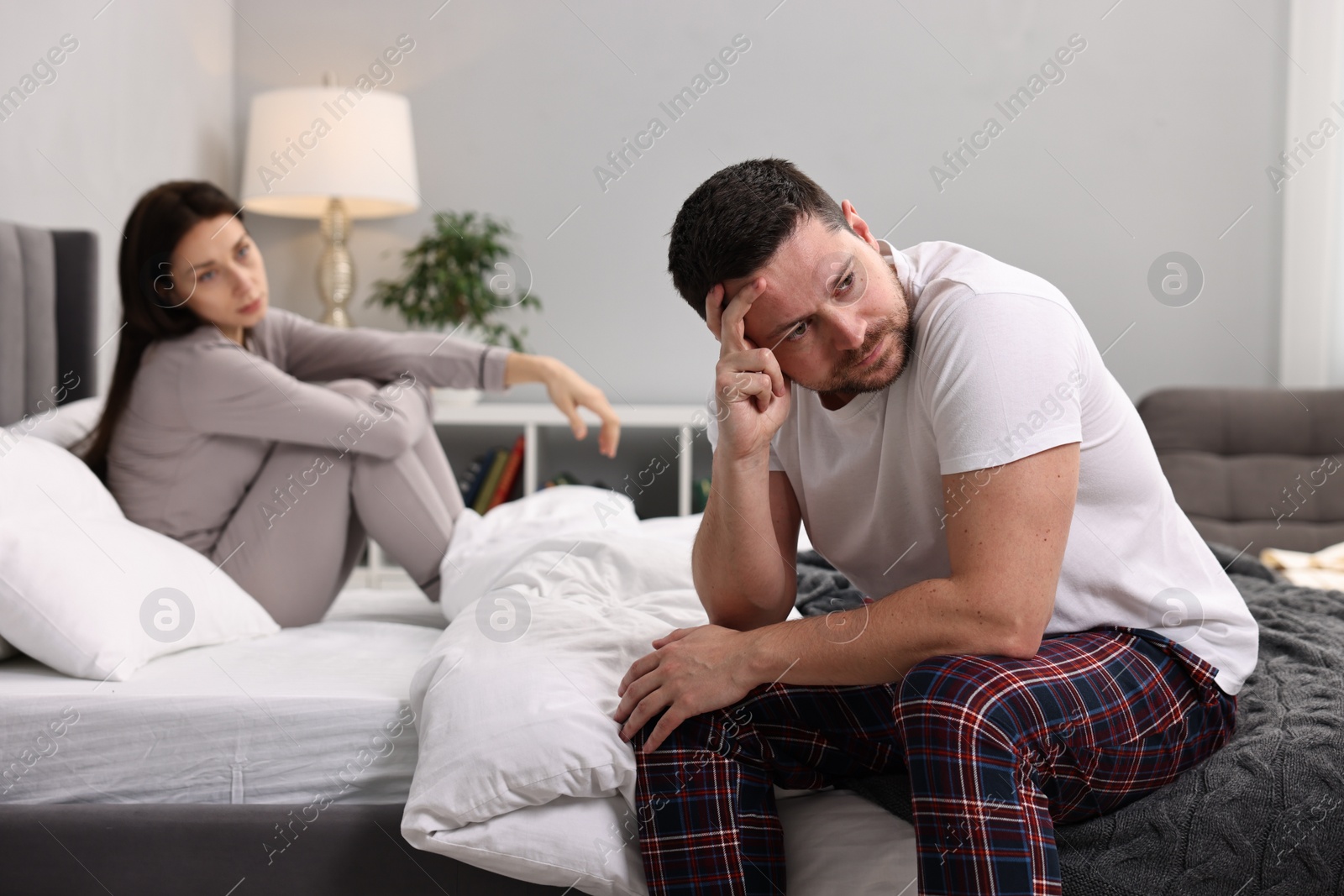 Photo of Offended husband ignoring his wife in bedroom, selective focus. Relationship problems