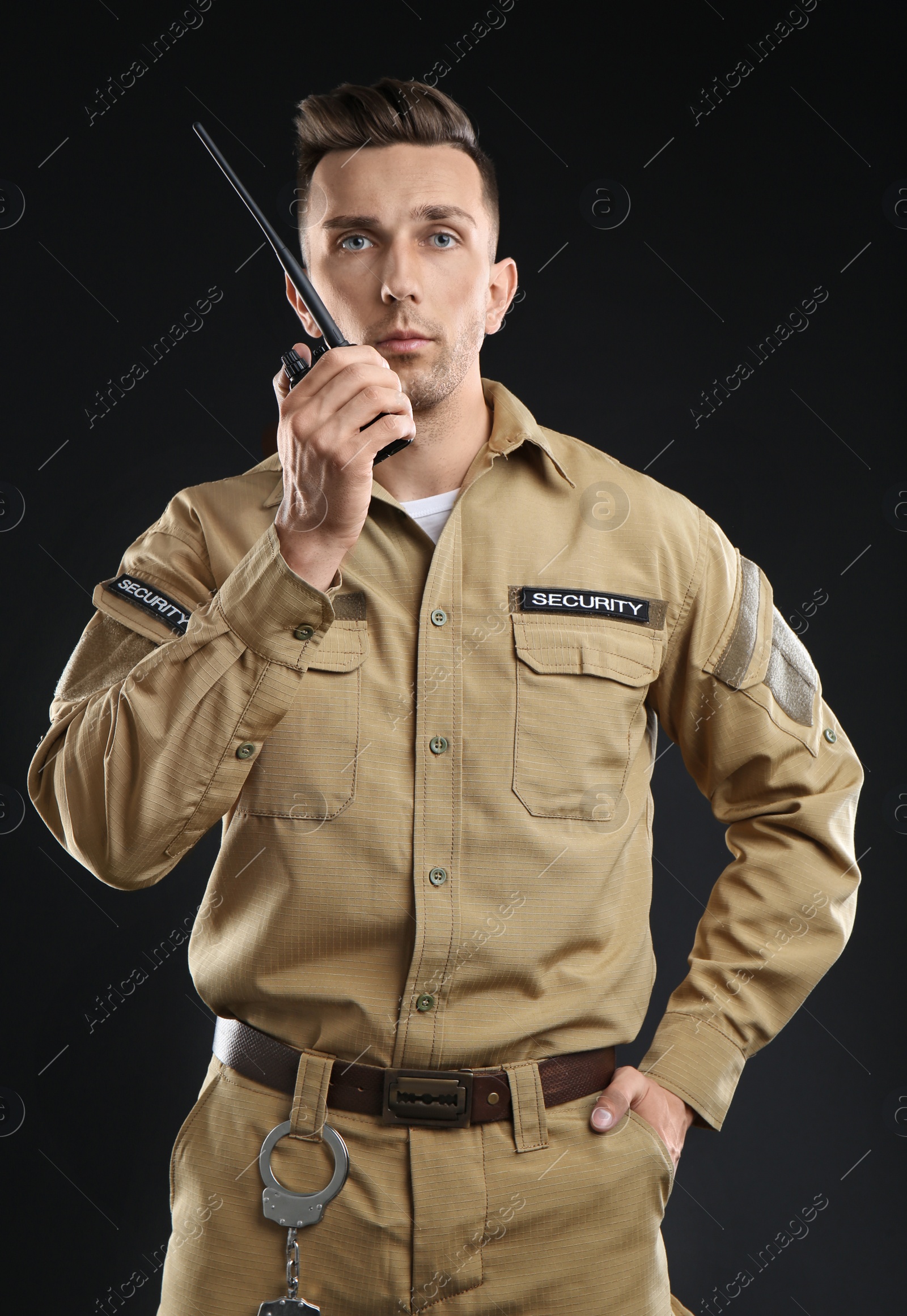 Photo of Male security guard using portable radio transmitter on dark background