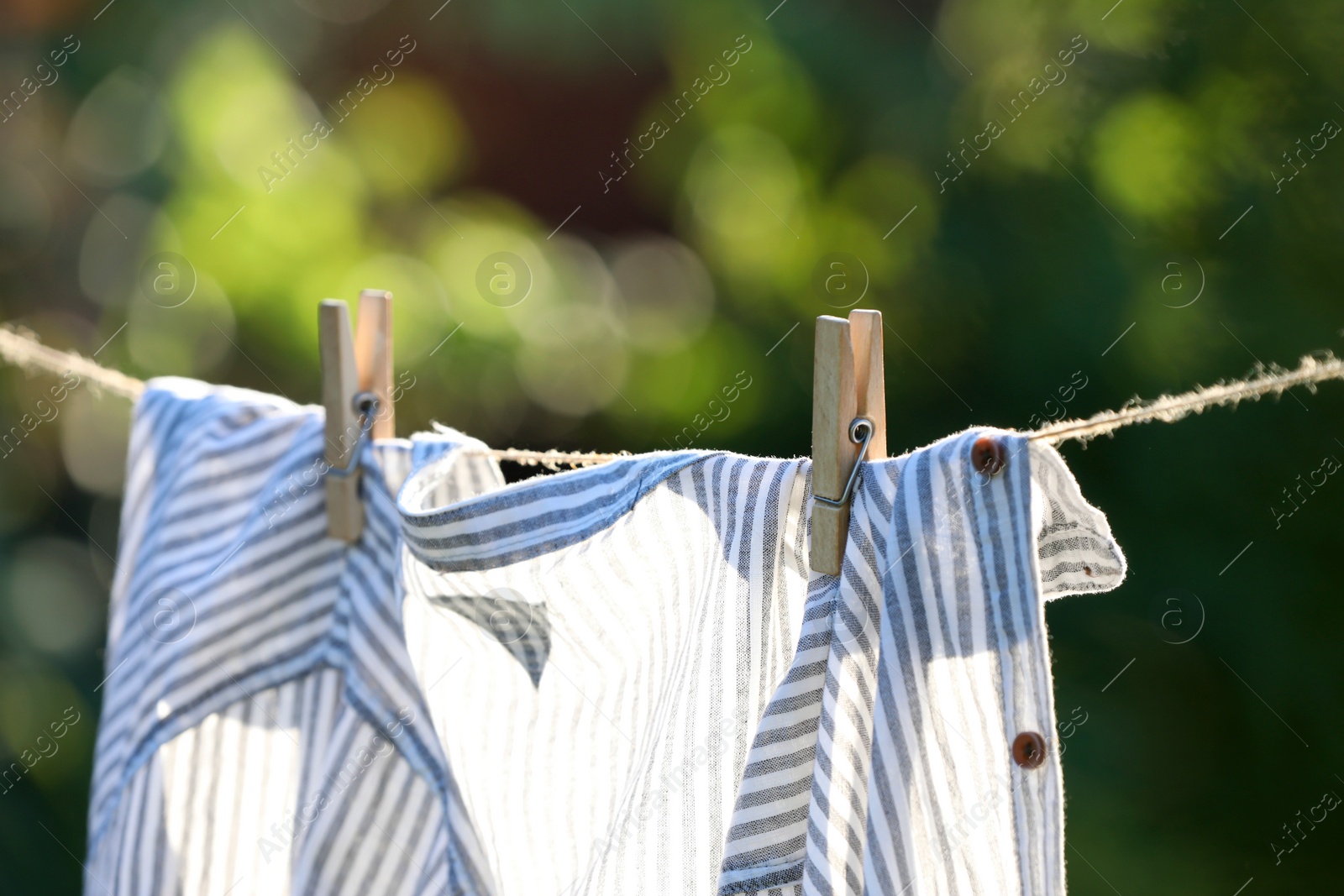 Photo of Washing line with drying shirt against blurred background, focus on clothespin