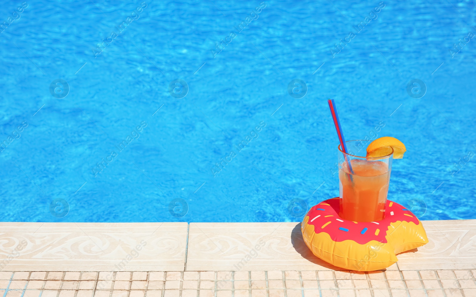 Photo of Tasty refreshing cocktail on edge of swimming pool