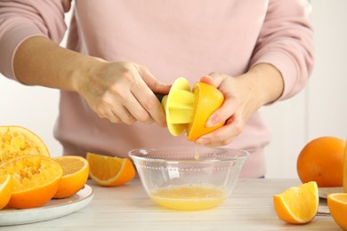 Photo of Woman squeezing orange juice at wooden table, closeup