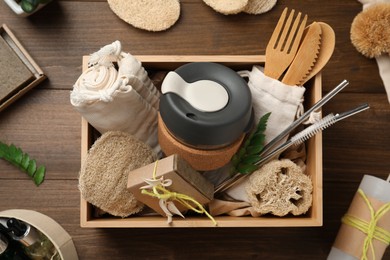 Photo of Crate with eco friendly products on wooden table, flat lay