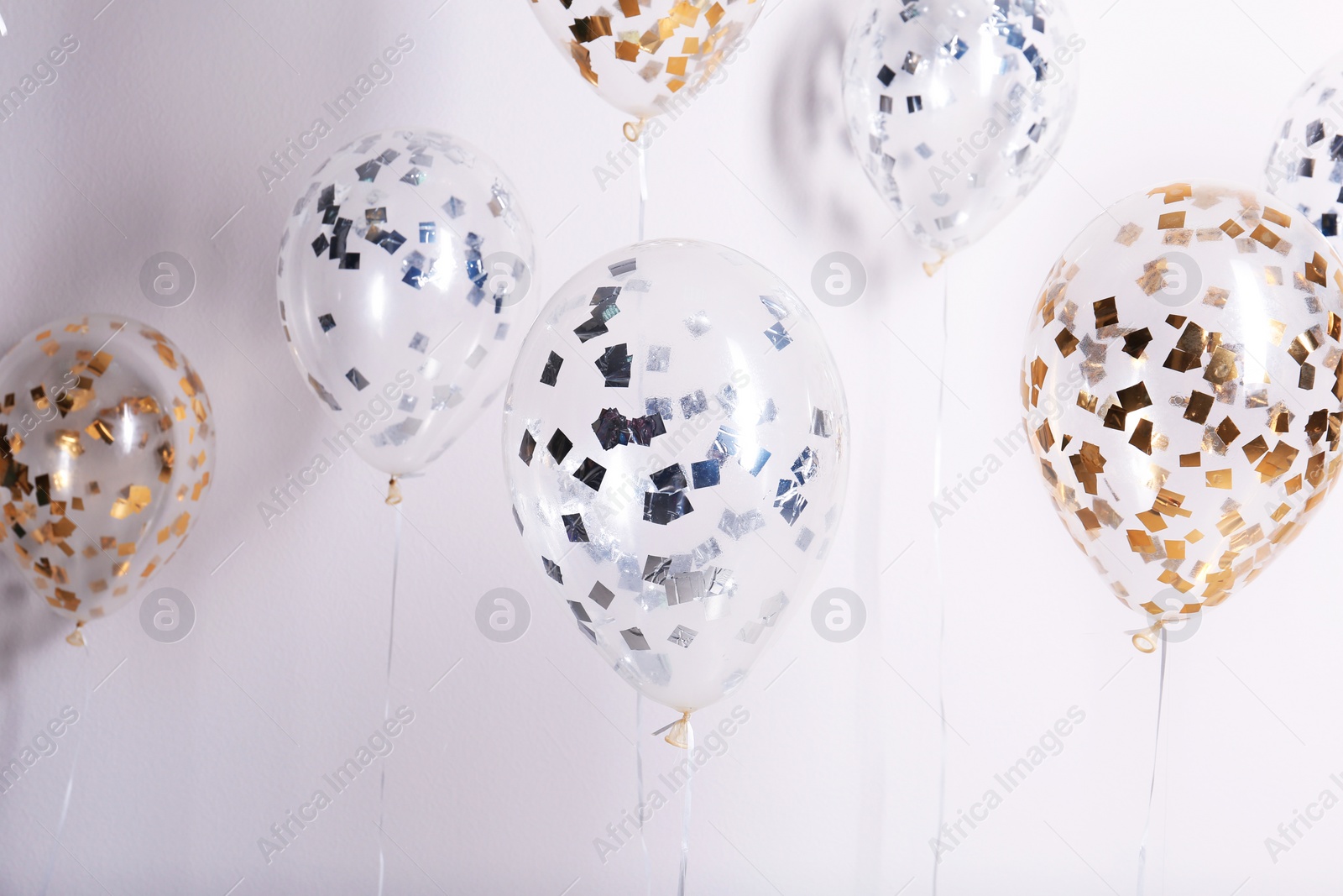 Photo of Bright balloons with sparkles on white background