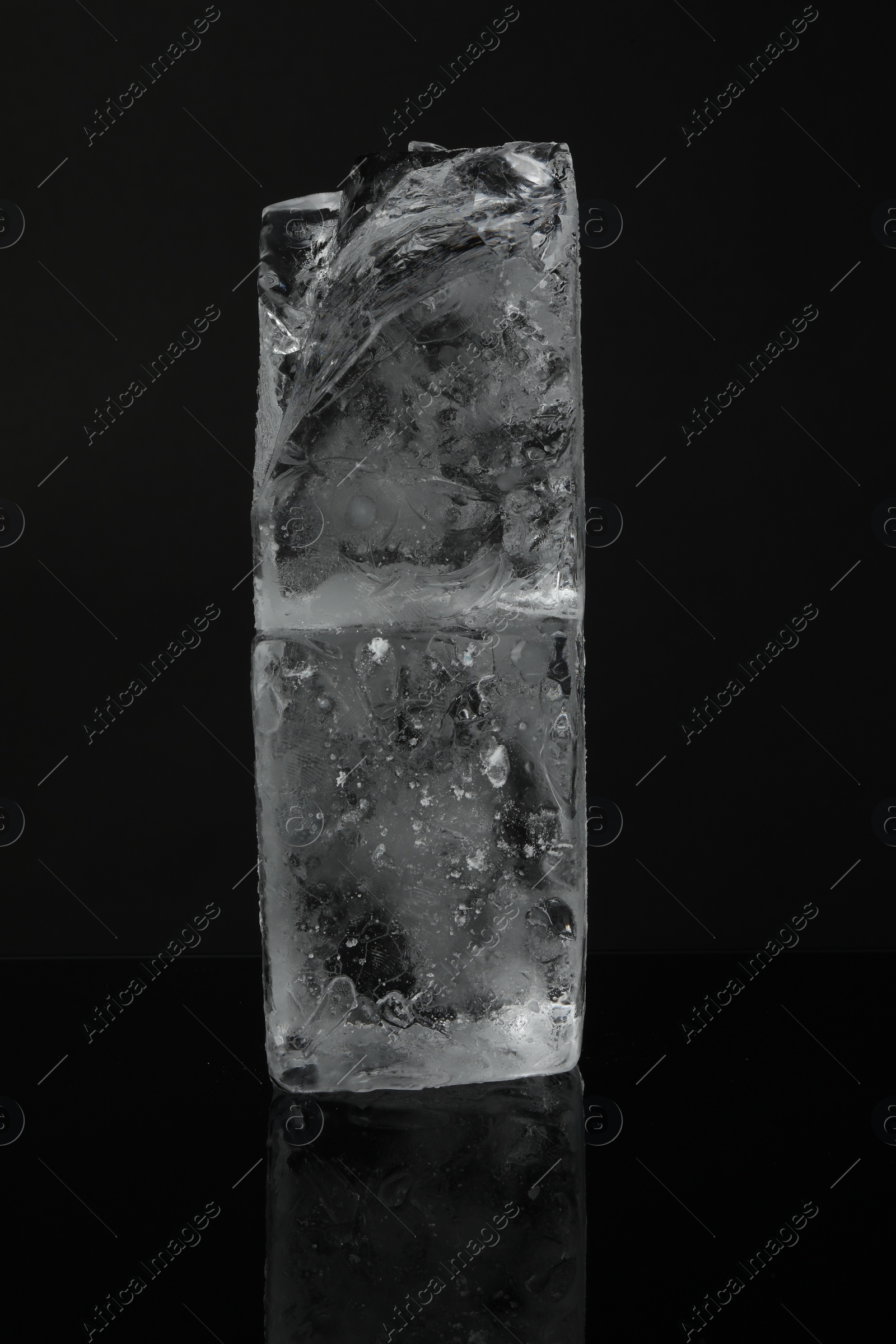 Photo of Blocks of clear ice on black mirror surface