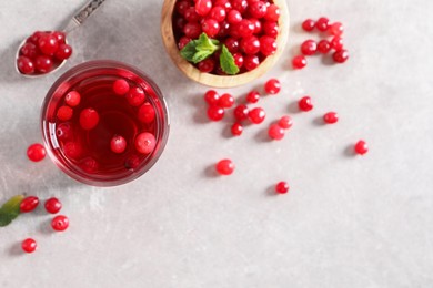 Photo of Tasty cranberry juice in glass and fresh berries on light grey table, top view. Space for text
