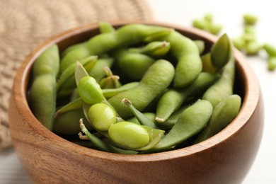 Bowl with green edamame beans in pods on table, closeup