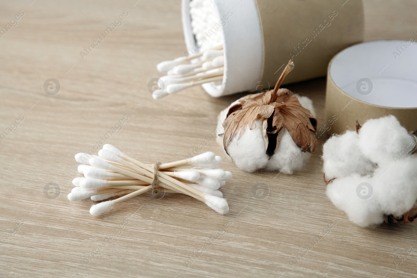 Photo of Cotton swabs and flowers on wooden table, closeup. Space for text