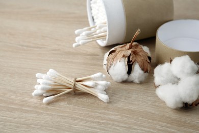 Photo of Cotton swabs and flowers on wooden table, closeup. Space for text