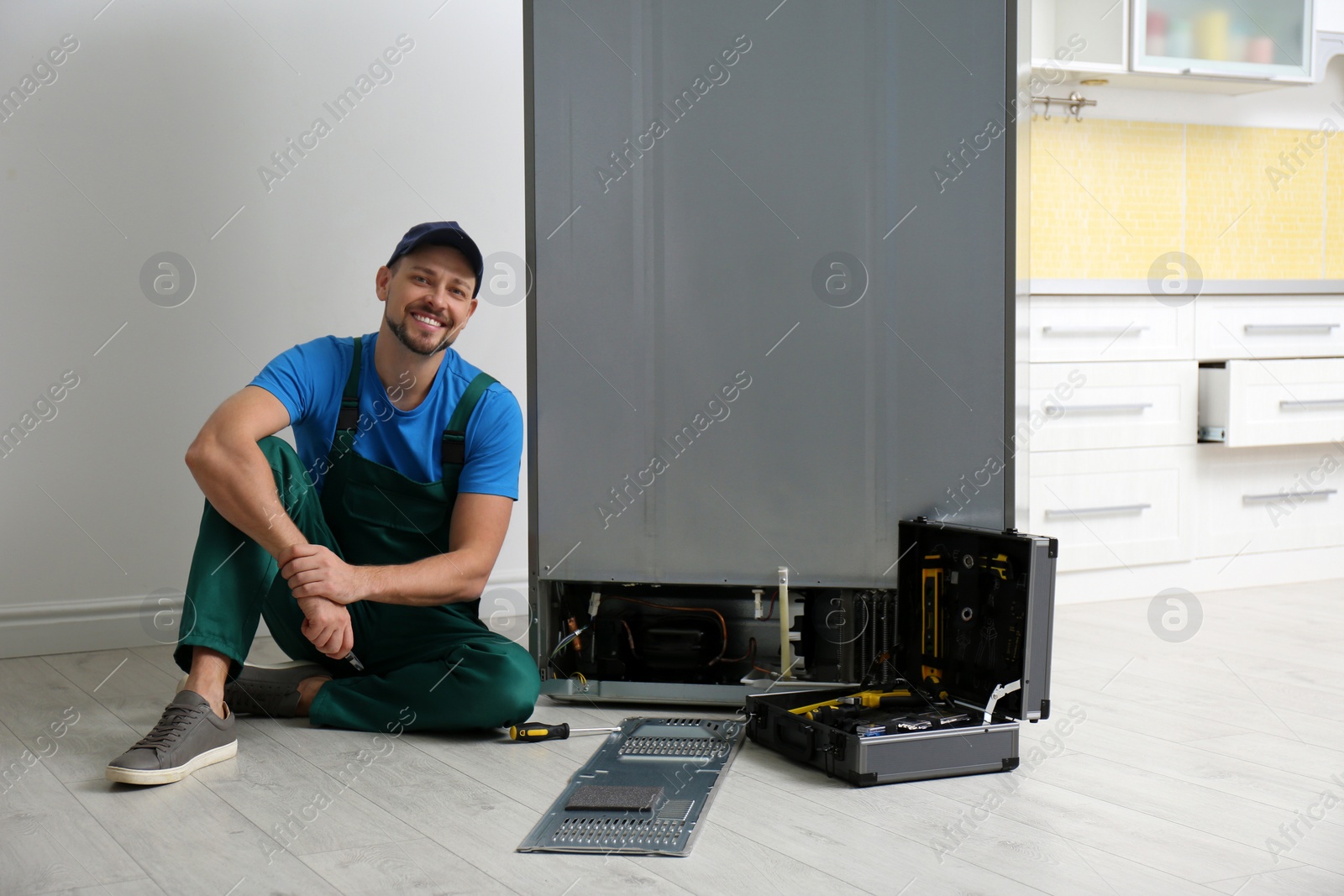 Photo of Male technician with pliers near refrigerator indoors