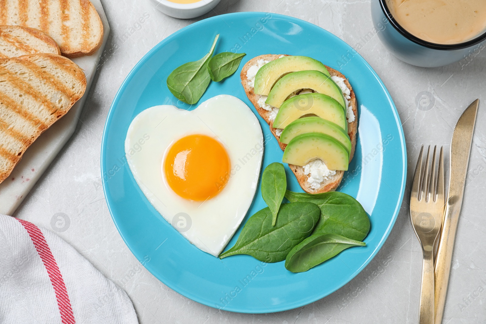 Photo of Romantic breakfast with heart shaped fried egg served on light grey table, flat lay