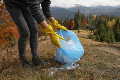 Photo of Woman with trash bag collecting garbage in nature, closeup