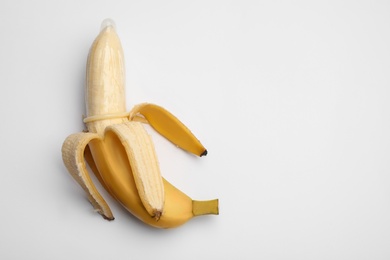 Photo of Banana with condom on white background, top view. Safe sex