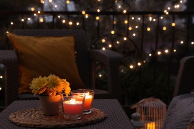Photo of Beautiful view of garden furniture with pillow, soft blanket and burning candles at balcony
