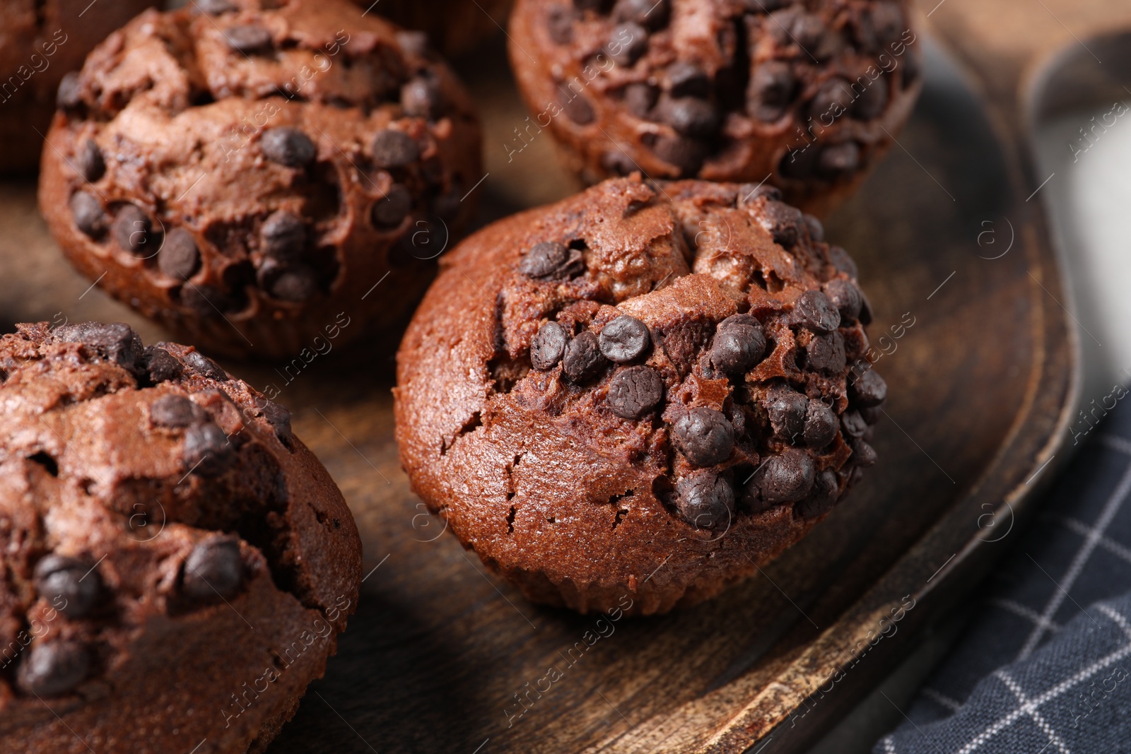 Photo of Tasty chocolate muffins on wooden serving board, closeup